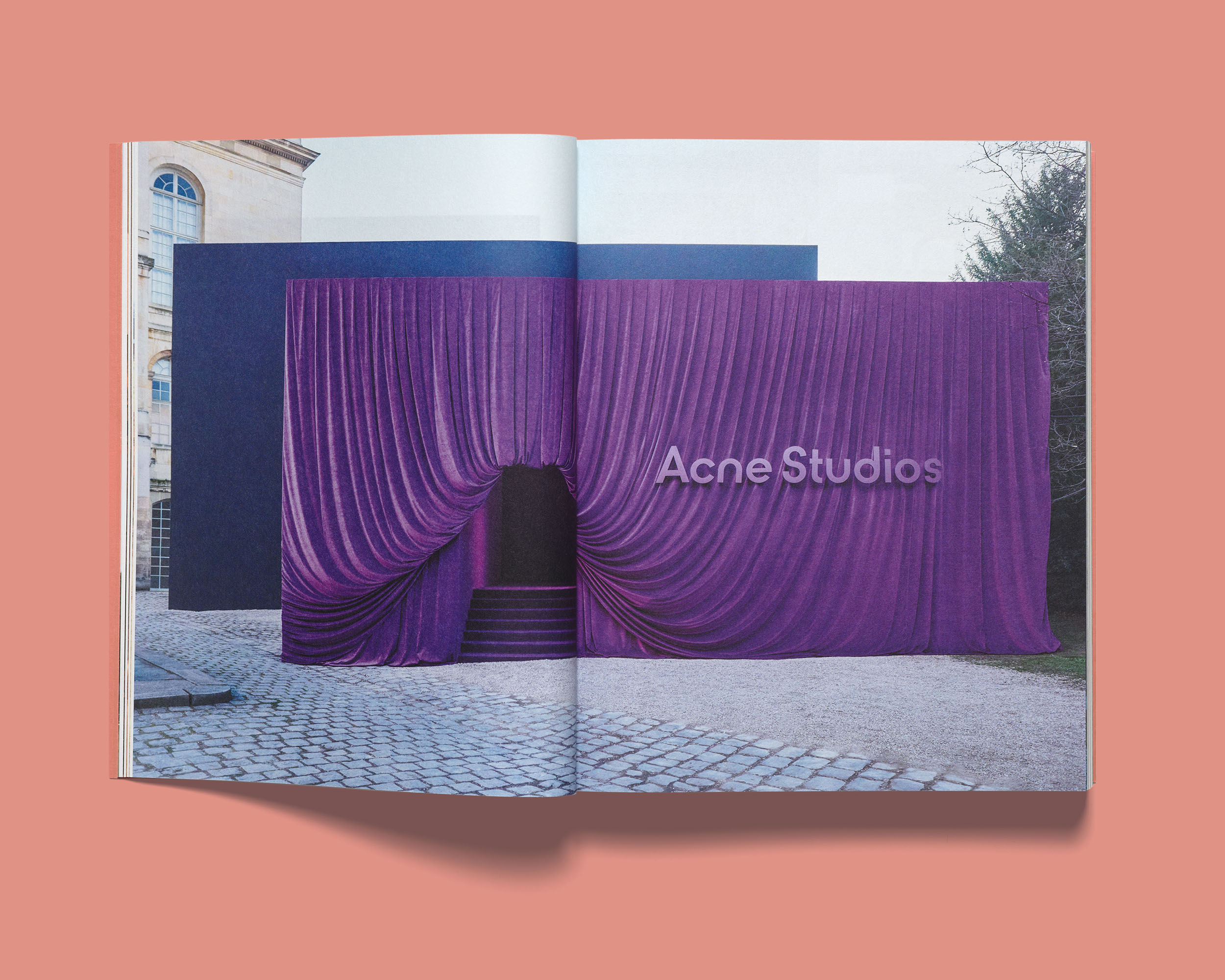 Open Acne Paper showing a double-page spread of an outdoor installation with large purple draped fabric facade.