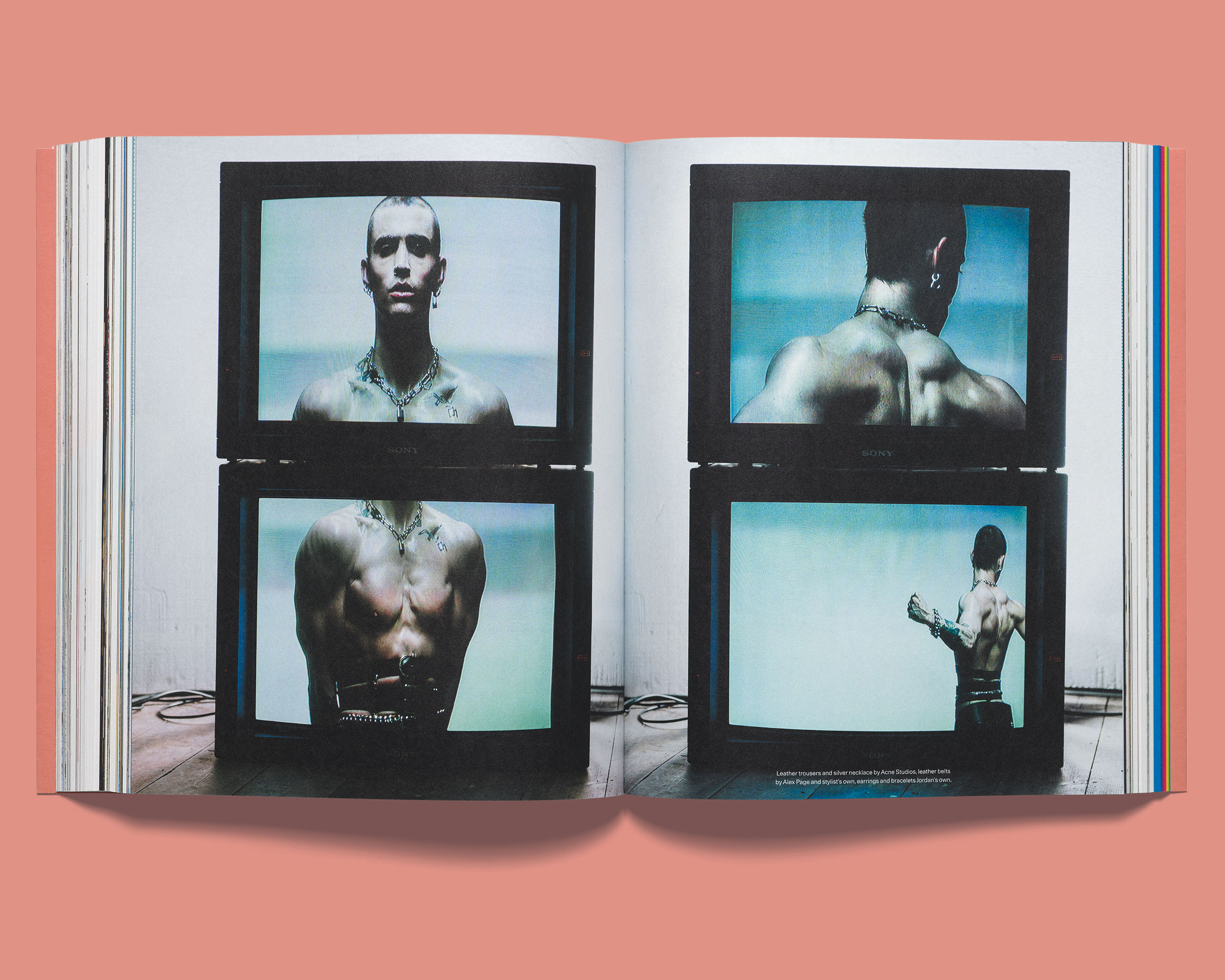 Open Acne Paper spread showing four CRT television screens displaying a figure wearing black leather trousers and a silver chain necklace.